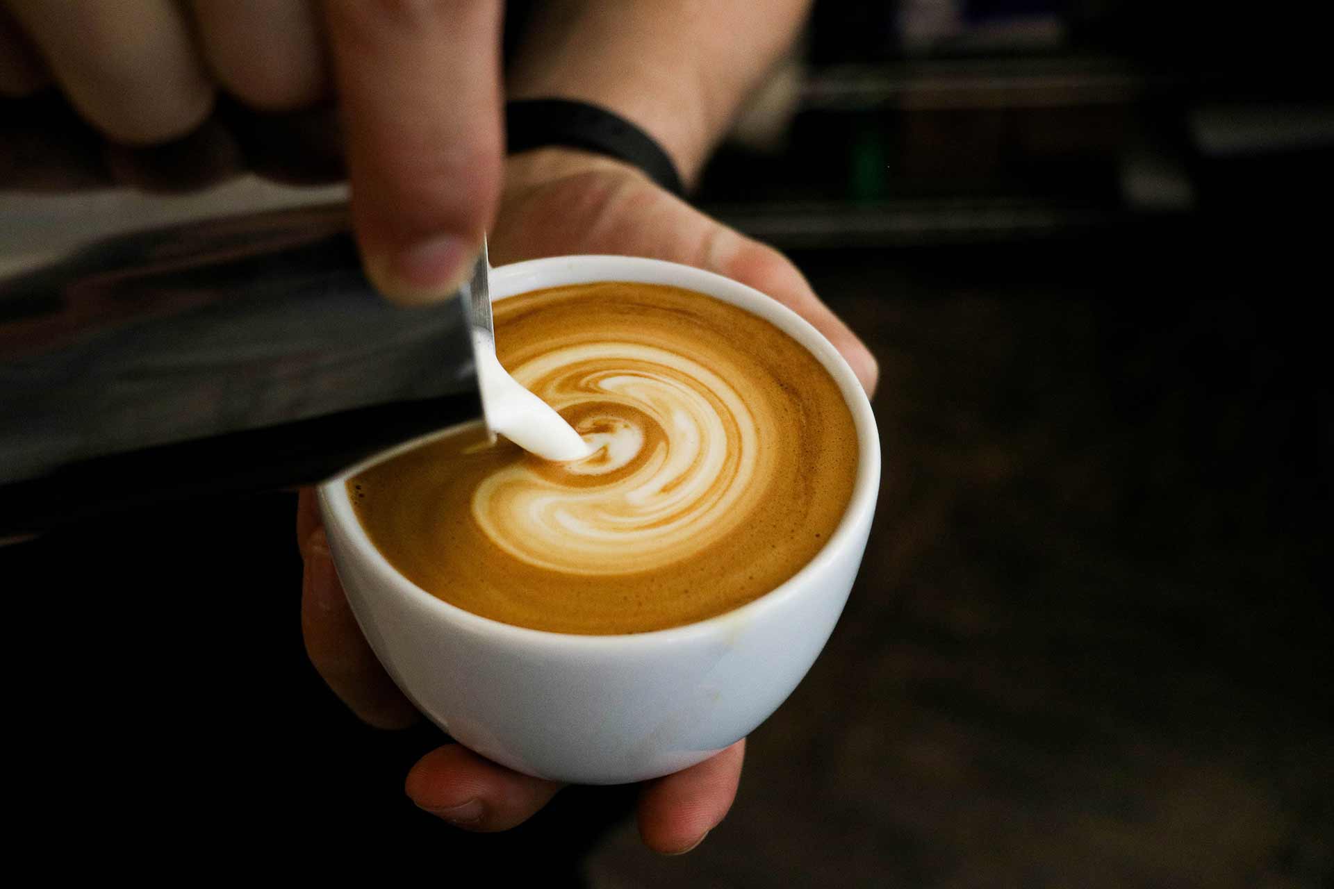 Eine Kaffeetasse, in welche Milch gefüllt wird